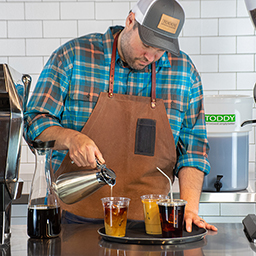 Barista pouring Toddy-brewed cold brew drinks in cafe